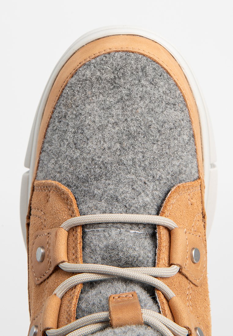 Plan rapproché d'un bout de sneaker en tissu en laine grise avec des accents en cuir beige, présentant des lacets gris et des œillets en métal sur une semelle blanche.