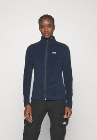 Marineblauwe fleece jas met een hoge kraag en een ritssluiting aan de voorkant, voorzien van een klein wit logo op de borst en een gestroomlijnd ontwerp.