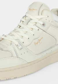 Голям план на бяла маратонка Pepe Jeans с бежова подметка, връзки и лого, отпечатано на езица и страничния панел.