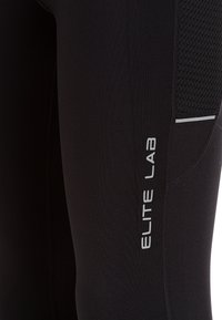 Zwarte sportlegging met een gladde textuur, voorzien van een meshpaneel, reflecterende accenten en het logo "ELITE LAB" in het wit aan de zijkant.