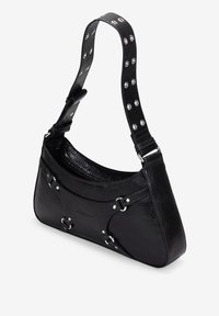 Bolso de hombro de cuero negro con forma curva, superficie texturizada, tachuelas metálicas en la correa y un bolsillo interior con cremallera.