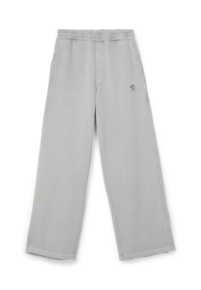 Pantalon gris clair à jambes larges avec taille élastique et poches latérales, comportant un petit logo noir sur la partie supérieure de la cuisse gauche.