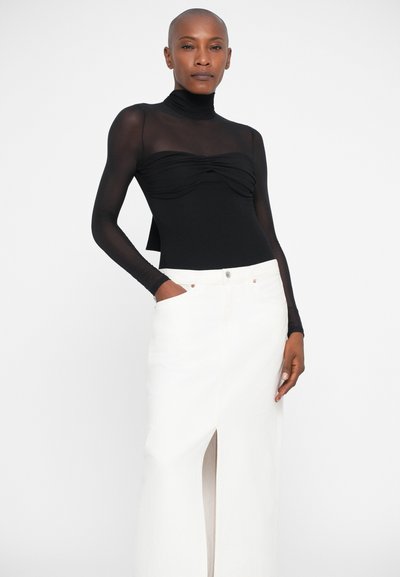 Sort langærmet bodystocking med en rynket front, parret med en hvid denimskirt med en frontslids og lommer. Rent, minimalistisk design.