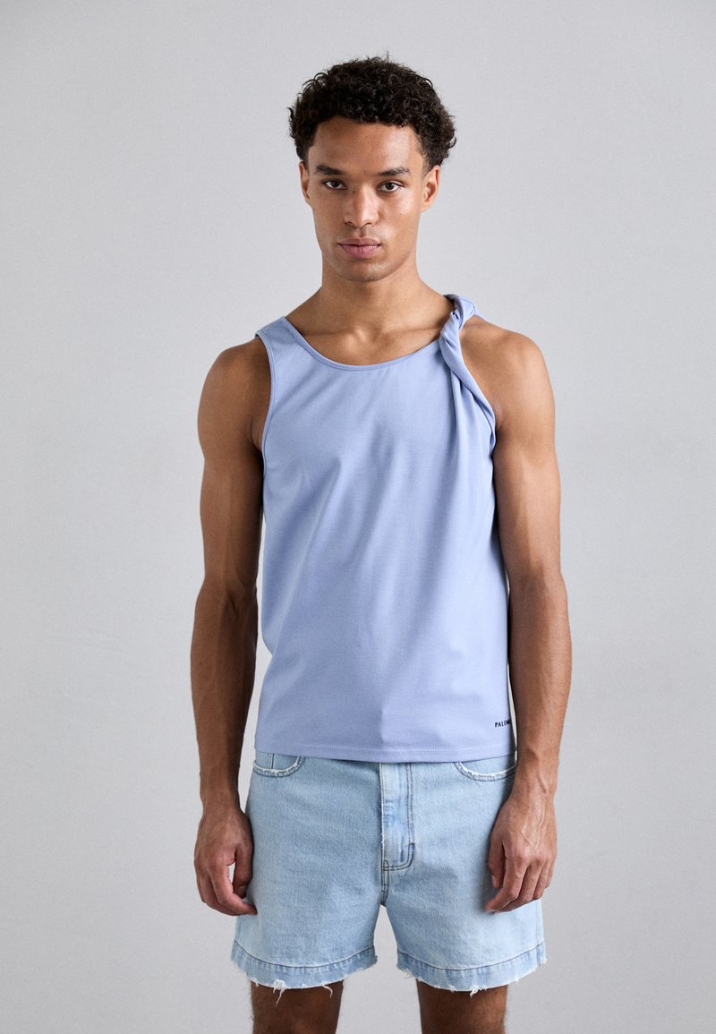 Light blue sleeveless tank top in smooth fabric with a twisted strap detail, paired with light denim shorts, worn by a male model.