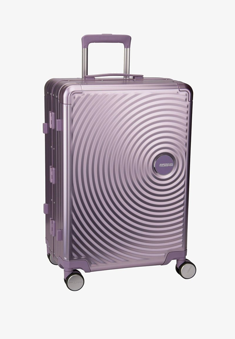 Lila Hartschalenkoffer mit konzentrischen Kreisdessins, Teleskopgriff, vier Spinner-Rädern und American Tourister-Logo.