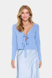 Lichtblauwe geribbelde gebreide cardigan met een diepe V-hals en twee strikjes voor. Lange mouwen, cropped lengte. Draagt over een glanzende lichtblauwe rok.