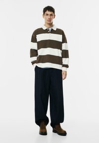 Brązowa i biała, paskowana, długosleeve polo, w połączeniu z luźnymi, ciemnymi dżinsami i brązowymi botkami kostkowymi. Casualowy, luźny krój.