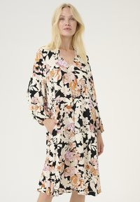 Gėlių suknelė su juodu fonu, puošta rožinėmis ir oranžinėmis gėlėmis. V formos iškirptė, ilgomis rankovėmis ir šoninėmis kišenėmis. Lygus audinio tekstūra.