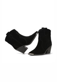 Botines de ante negro con punteras afiladas, costuras curvadas y un bajo tacón de bloque. Presentan una puntera metálica y lengüetas en la parte trasera para facilitar su colocación.