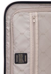 Intérieur de valise beige avec compartiments en tissu zippés et en mesh, doublure en tissu de marque Wittchen, et étiquette cousue avec les informations sur le produit.