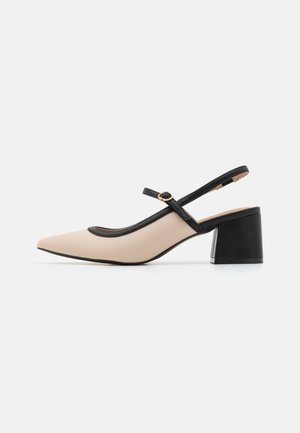 Beige slingback sko med spids tå, sort piping og en kraftig sort hæl. Justerbar rem med en metalspænde detalje.