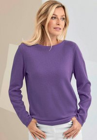 Lila Strickpullover mit rundem Ausschnitt und langen Ärmeln, ausgestattet mit einer glatten Textur und gerippten Bündchen, kombiniert mit hellen Hosen.