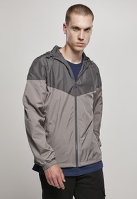 Letvægts,zip-up jakke i grå nuancer med hætte. Har elastiske manchetter og sidelommer. Glat, vandafvisende stof.