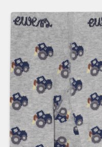 Gray socks featuring a repeated tractor pattern in navy, brown, and gray with yellow accents; soft knit texture; logo near the top.