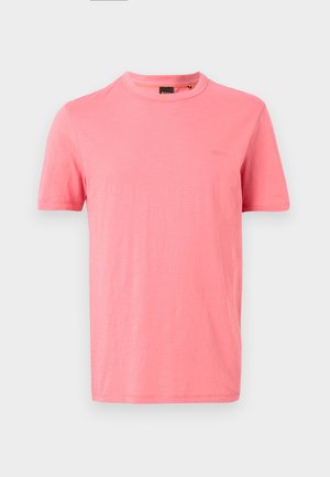 T-shirt uni rose corail à manches courtes avec col rond et logo de marque en relief discret sur le côté gauche de la poitrine sur fond blanc.