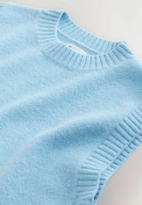 Lichtblauwe gebreide trui met een ribbelige ronde hals en korte mouwen. Zachte textuur met een gladde afwerking voor extra comfort.