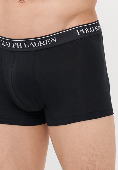 Črne bombažne boksarice z kontrastnim elastičnim pasom, na katerem je bel logo "Polo Ralph Lauren". Gladka tekstura, prilegajoča se oblika.