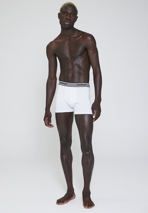 Hvide boxer shorts lavet af blødt stof, med en sort-stribet elastisk talje. Beklædningen har en tætsiddende pasform og glat tekstur.