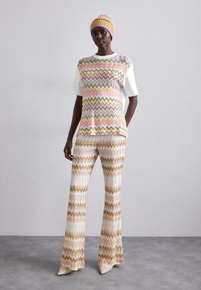 Ensemble tricoté comprenant un haut à manches courtes et un pantalon évasé avec des motifs en zigzag de rose, jaune et beige. Texture durable et douce, avec une coupe ajustée.