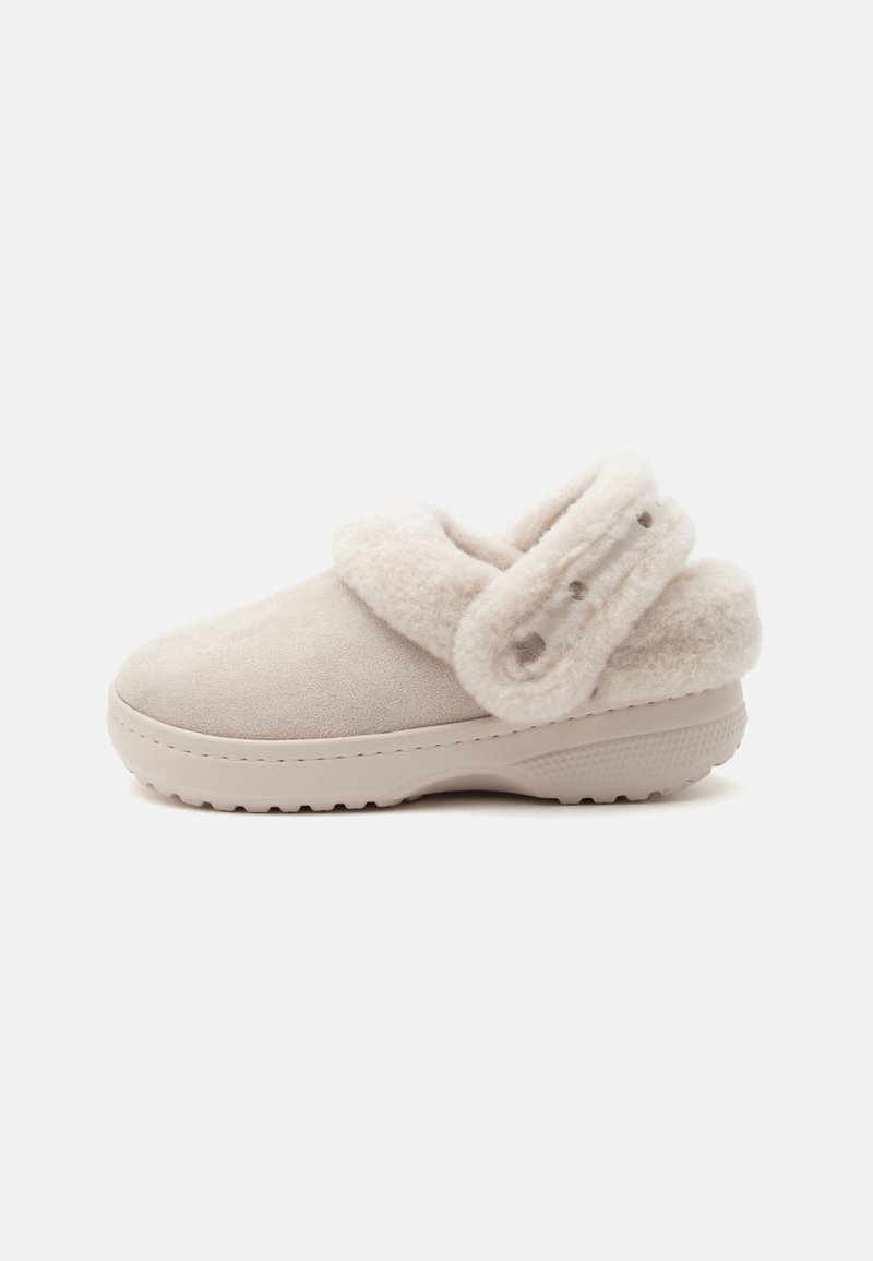 Sabot beige clair à enfiler avec doublure douce en peluche et bride ajustable à l'arrière, avec une semelle texturée pour une bonne adhérence.