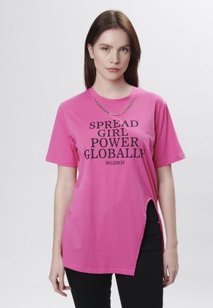 Roze oversized t-shirt met korte mouwen, zijsplit en zwarte bedrukte tekst "SPREAD GIRL POWER GLOBALLY INFLUENCER."