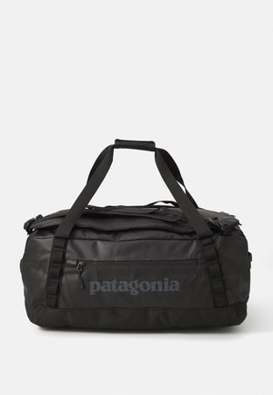 Black Patagonia duffel bag with dual carrying straps and zippered front pocket on a white background.