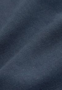 Gros plan sur un tissu bleu foncé avec une texture en maille douce et fine, avec de subtils plis ondulés.