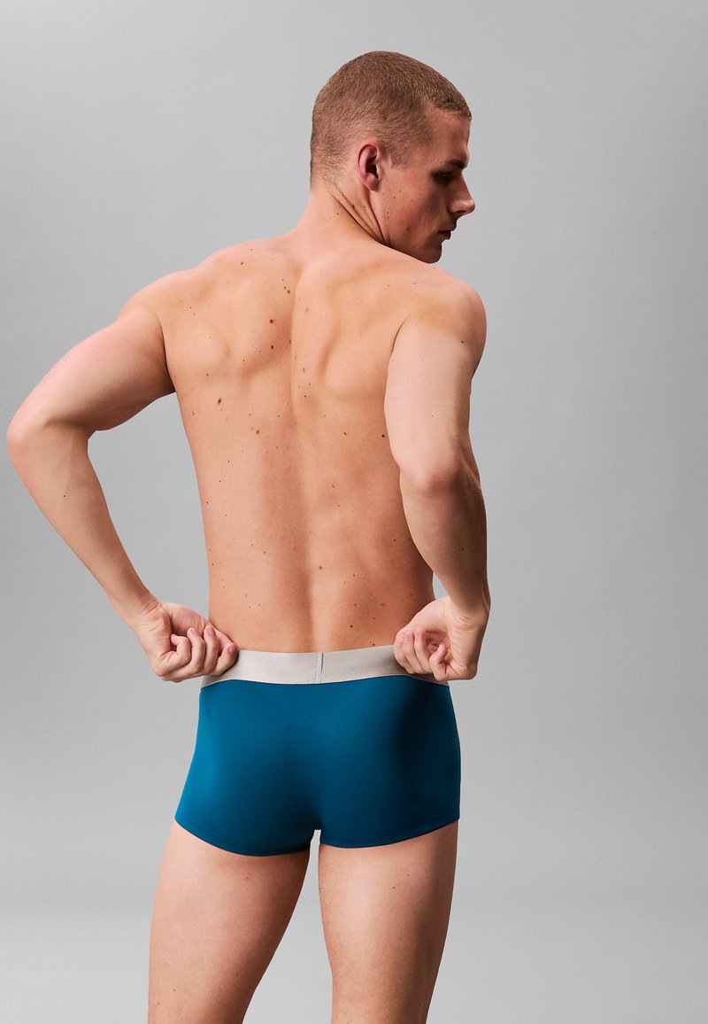 Boxers couleur sarcelle avec une ceinture élastique gris clair, vus de dos, présentant un design lisse, ajusté et avec des coutures minimales.