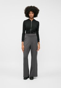 Μαύρο φούτερ με φερμουάρ, γκρι παντελόνι με φαρδιά πόδια. Απαλή ύφανση, λεπτομέρειες με φερμουάρ και πλαϊνές τσέπες στο φούτερ. Το παντελόνι έχει καλή εφαρμογή στη μέση.