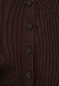 Σκούρο βυσσινί ριμπ κασκόλ με πέντε μεγάλα σκούρα κουμπιά μπροστά, ορατή υφή και ζεστό πλεκτό ύφασμα.