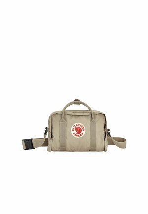 Sac Fjällräven Kånken beige compact avec poignées supérieures, bandoulière ajustable et logo circulaire rouge sur la poche avant.