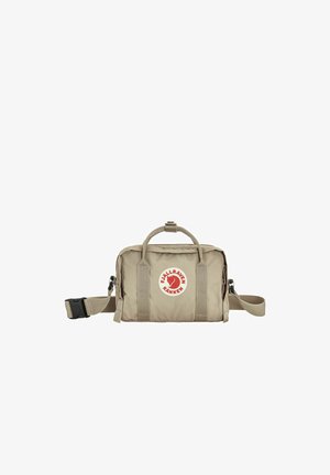 Sac Fjällräven Kånken beige compact avec poignées supérieures, bandoulière ajustable et logo circulaire rouge sur la poche avant.