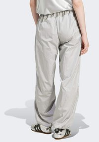 Ljusgrå, lätta byxor har ett elastiskt midjeband, en avslappnad passform och subtil lyster. Tyget är slätt med en något krinklad textur.