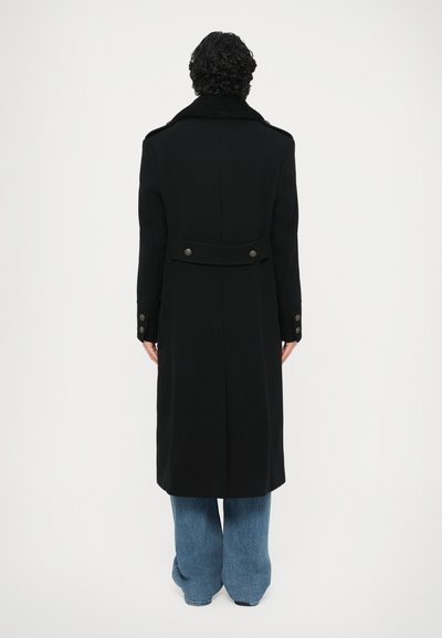 Abrigo largo negro con un amplio cuello, puños abotonados y detalle de cinturón en la espalda. Fabricado con una tela suave, diseñado para un ajuste holgado.