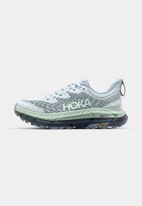 Vaaleansiniset juoksukengät, joissa on teksturoitu verkko-osa, HOKA-logo, vihreä välipohja ja kestävää mustaa ulkopohjaa, jossa on Vibram-brändäys.