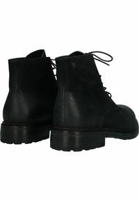 Botas de cuero negro hasta el tobillo con texturas mate y suaves, puntera redonda, diseño con cordones y suelas de goma gruesas. La vista trasera muestra detalles de costura.