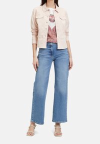 Světle růžová džínsová bunda přes bílou košili s růžovým paisley vzorem, kombinováno se světle modrými volnými džínami a béžovými sandály.