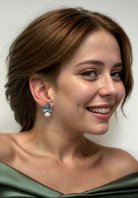 Pendientes florales en teal con pétalos texturizados y una gota de perla blanca. El diseño cuenta con un detallado intrincado y una forma tridimensional.