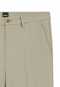Beige maßgeschneiderte Hose mit glatter Textur, geknöpftem Bund, zwei seitlichen Taschen und dezenten Nähdetails. Etikett oben sichtbar.