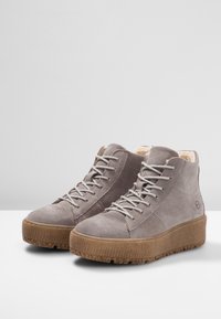 Szare zamszowe buty wysokie z tanowym teksturowanym gumowym spodem, kremową podszewką i szarymi sznurówkami. Widoczne przeszycia boczne i detal z logo.