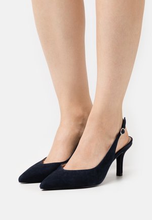 Escarpins à talons slingback en daim bleu marine avec un bout pointu, présentant un design élégant et un petit accent argenté sur la sangle.