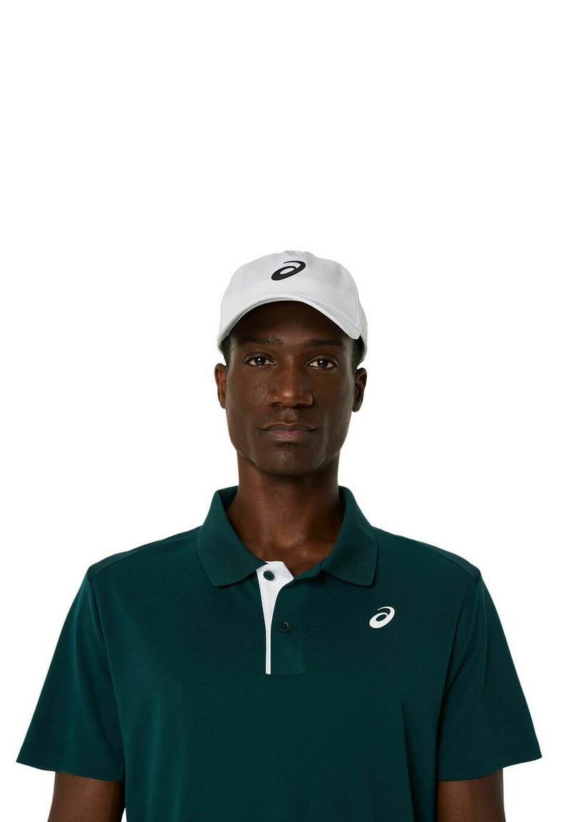 Cappello bianco con logo, polo verde scuro, patta a due bottoni, con dettagli bianchi sul colletto. Tessuto liscio, design aderente, maniche corte.