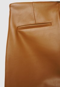 Brauner Lederrrock mit glatter Textur, strukturiertem Design und einer einzelnen horizontalen Tasche auf der Rückseite. Nahtdetails an der Taille.