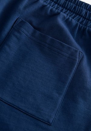 Marinblå bomullsshorts med elastisk midja och en rektangulär bakficka med sydda kanter för ökad hållbarhet.