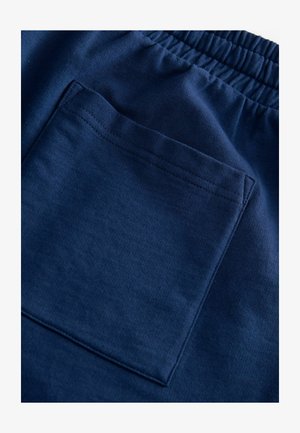 Mørkeblå bomuldsbukser har en elastisk talje og en rektangulær baglomme med syede kanter for øget holdbarhed.