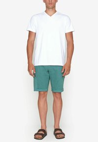 Vit bomull V-ringad t-shirt, gröna cargoshorts med sidofickor och bruna sandaler; avslappnad och ledig passform med uppvikta shorts.
