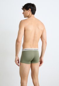 Herren Boxershorts in Olivgrün mit einem elastischen Bund in Weiß und Schwarz mit Streifen, tailliertem Schnitt und glattem Stoff. Rückansicht gezeigt.