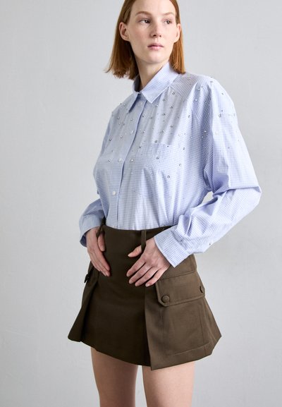 Ανοιχτό μπλε καρό πουκάμισο με κουμπιά και διακοσμητικά στοιχεία; συνδυασμένο με καφέ μίνι φούστα που διαθέτει μπροστινές τσέπες και δομημένο σχέδιο.