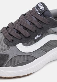 Grått stoff og semsket sneaker med hvit sidestripe, med grå lisser og en teksturert såle. Vans-logo på tungen.