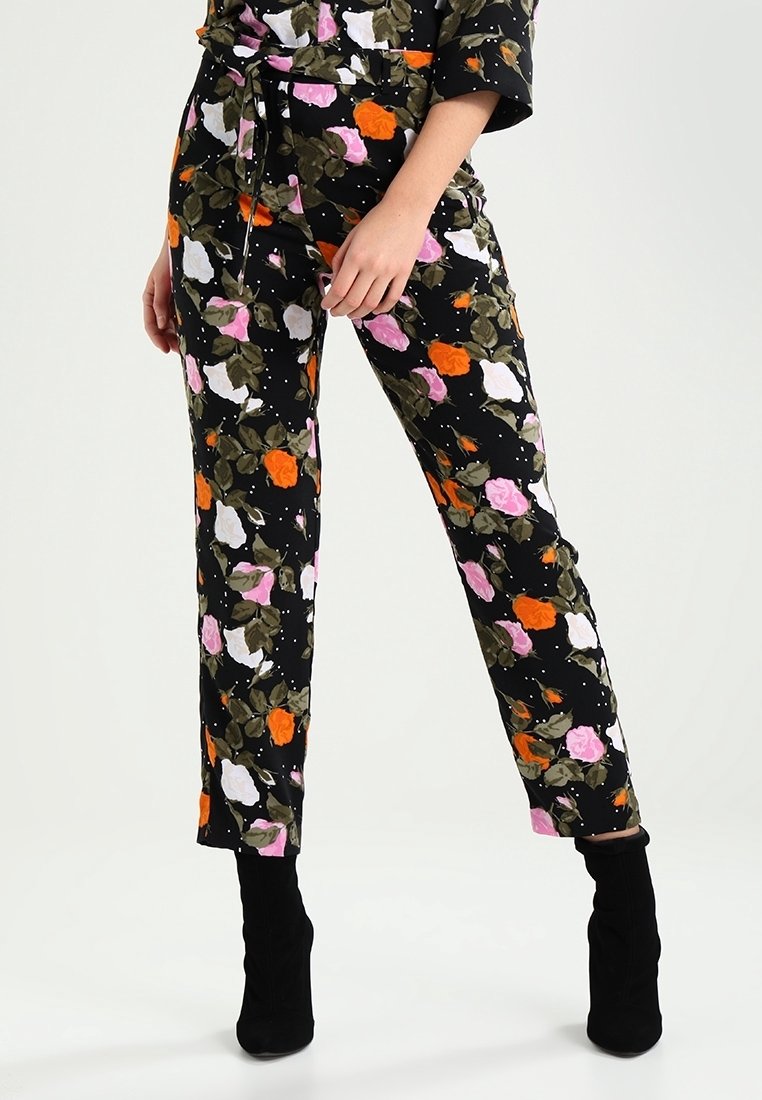 Pantalons floraux avec un fond noir, ornés de roses roses, oranges et blanches, de feuilles vertes, et d'une coupe ajustée.